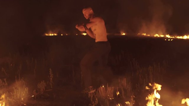 Military man training free fight at night bonfires. 4K