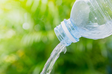 close up drinking water pouring from a plastic bottle on green background