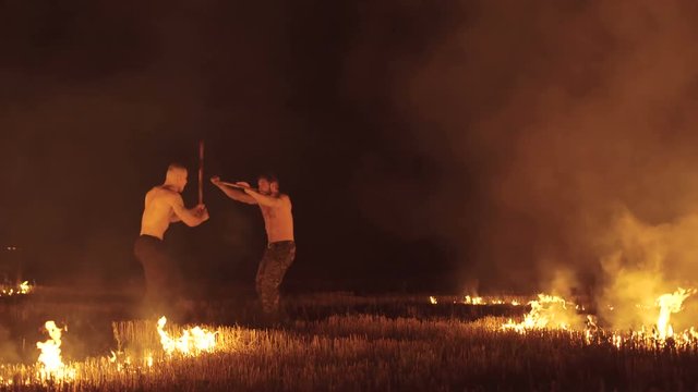 Free fighters beating with torches at night fires in field. 4K
