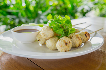 grilled meat ball with chilly saucec and cucumber put on the white dish with on wood table