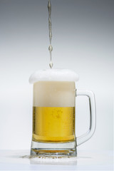 glass of beer with foam on a gray background