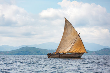 Pirogue artisanale en pleine mer avec sa voile hissée entre nosy be et nosy komba Madagascar - obrazy, fototapety, plakaty