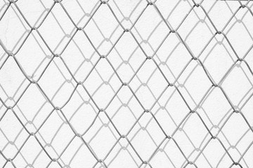 Wire mesh and shadow on white concrete wall.