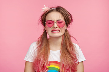 Desperate coquette woman going to cry, has sorrorful expression, regrets her actions, makes big mistake or failure, frowns face. Miserable female poses in pink studio, expresses negative emotions