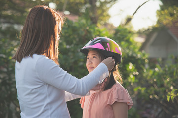 mother wears a bicycle helmet to her daughter