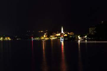 Fototapeta na wymiar night on Pescatori Island, one of the Borromean Islands of the Maggiore Lake, which rises the dark water with the reflections of its lights