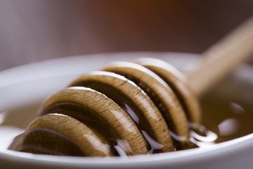 Honey in jar with honey dipper on wooden background 