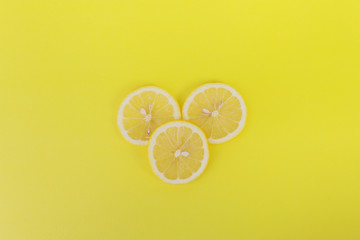 Three fresh lemon slice on yellow background.