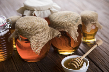 Honey dripping from a wooden honey dipper in a jar