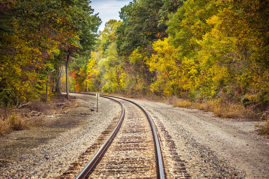 Railway Track With A Curve Surrounded By Trees In Autumn Colors