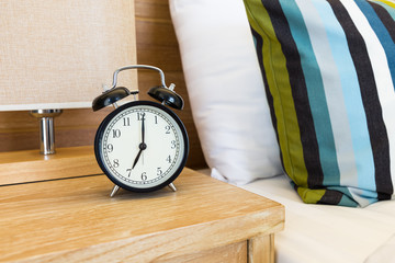 Vintage retro alarm clock on bed side table at 7 o'clock