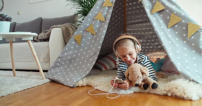 Girl using phone listening music in bivvy at home