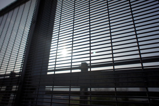 looking through a steel barrier grid at the sun