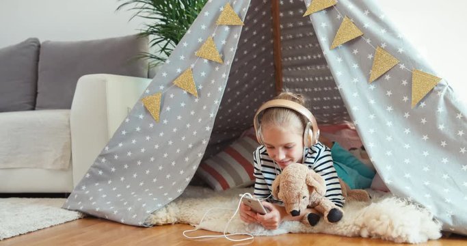 Girl using phone listening music in bivvy in home