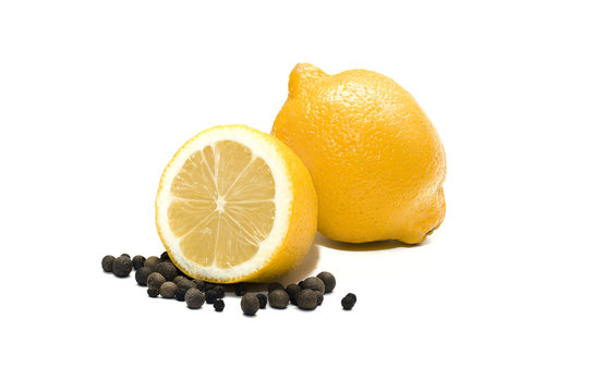 Lemon and black pepper. One whole lemon and its half and black pepper in peas isolated on white background