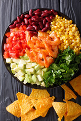 Salad with prawns, vegetables and nachos close-up. Vertical top view