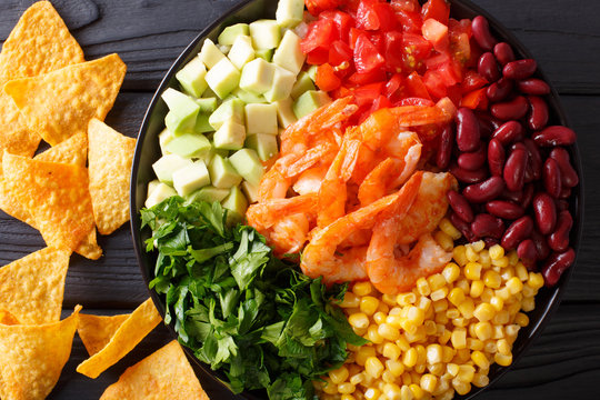 Mexican salad with shrimps, beans, corn, avocado and greens close-up. horizontal top view