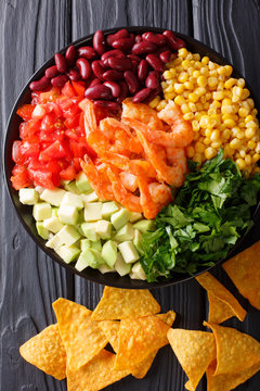 Salad with prawns, vegetables and nachos close-up. Vertical top view