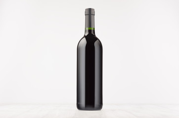Black wine bottle with red wine on white wooden board, mock up. Template for advertising, design, branding identity.