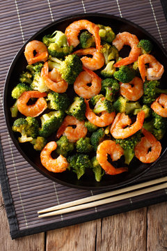 healthy food: stir fry shrimp with broccoli closeup. Vertical top view
