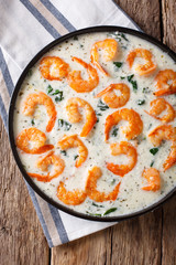 Spicy prawns with spinach in creamy cheese sauce close-up on a plate. Vertical top view