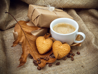 a coffee with a cookie in the form of hearts on a retro background, with gifts and an autumn leaf