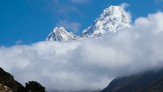 Time lapse. The movement of clouds near the majestic Mount Ama Dablam. Track to the base camp of Everest in the Himalayas. On the trail walk porters and trackers. Sagarmatha National Park, Nepal