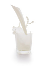 Pour the milk into a glass and Splash the milk with a white background.