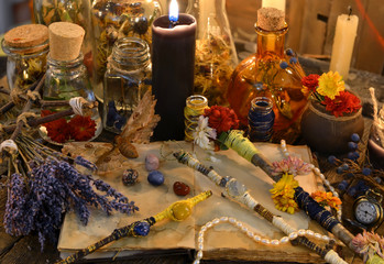 Magic wands, open diary book, lavender flowers and black candle on witch table