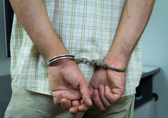 A criminal in handcuffs. With hands on your back. Arrested in his office
