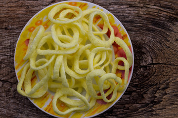 Plate with crispy snacks onion rings on wooden table