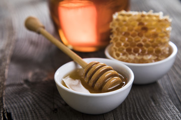 Honey in jar with honey dipper on wooden background 