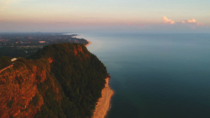 Aerial view. Cliff by the sea turned into red color during sunrise.