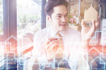 Businessman holding a little house over coffee shop background house business ideas concept