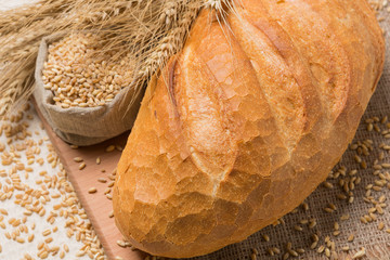 fresh bread on a wooden board, composition with wheat ears, grains and flour