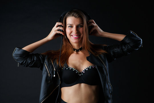 Image of young woman wearing headphones in leather jacket