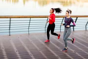 Obraz premium Two young women running by river
