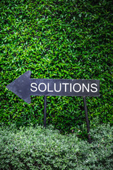 solutions signage arrow with background of fence green tree