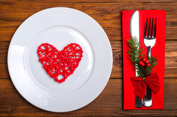 Christmas table: knife and fork, plate, napkin and Christmas tree branch on a wooden table top view with copy space.