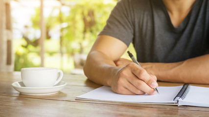 Man writing on a notebook in a cafe.