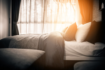 Fototapeta premium Bed maid-up with clean white pillows and bed sheets in beauty room. Close-up. Lens flair in sunlight.