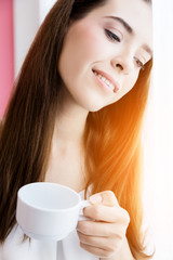 beautiful happiness caucasian girl enjoy morning moment with hot coffee in white tshirt with light from white curtain