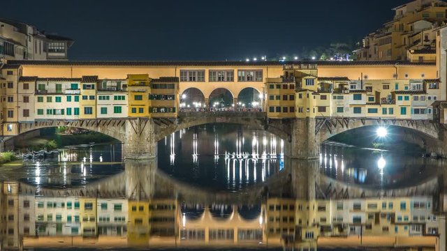 Famous Ponte Vecchio bridge timelapse over the Arno river in Florence, Italy, lit up at night