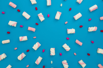Colored candy and marshmallow on blue background. Flat lay, top view