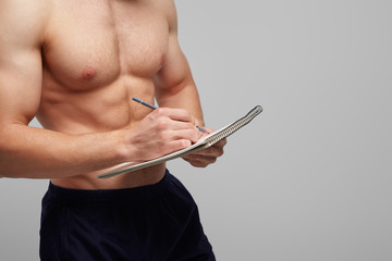 Muscular man writing in notepad