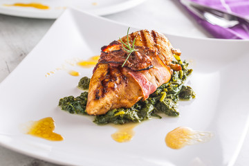 Chicken grill breast. Chicken roasted breast with bacon and spinach on white plate. Culinary food  in hotel pub or restaurant