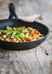 rosted chanterelles and potatoes with spring onions served in a black pan