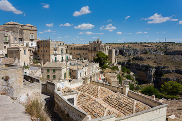 Fototapeta na wymiar panoramic view of typical stones (Sassi di Matera) and church of Matera UNESCO European Capital of Culture 2019 under blue sky. Basilicata, Italy