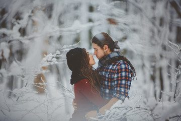 Young couple in love kissing in winter forest