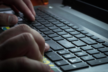 Men's hands are typing on the laptop's keyboard